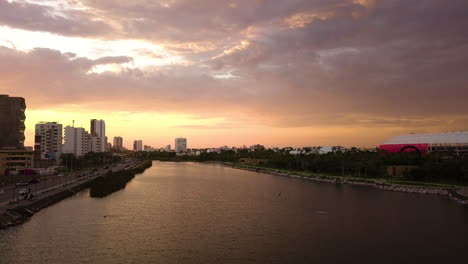 Vista-Aérea-De-La-Puesta-De-Sol-De-Un-Río-Que-Pasa-Por-Un-área-Urbana