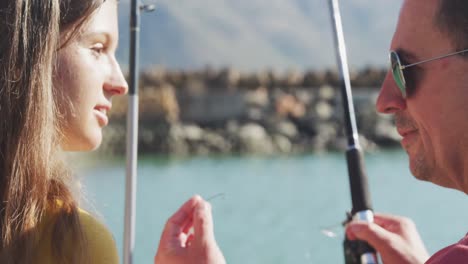 vista lateral de cerca de un hombre caucásico y su hija adolescente lado del puerto de pesca