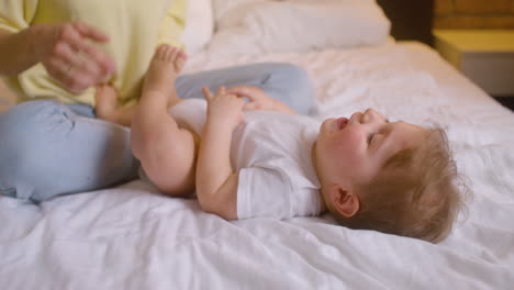 Mujer-Jugando-Con-Su-Bebé-Mientras-Está-Sentada-En-La-Cama-En-El-Dormitorio