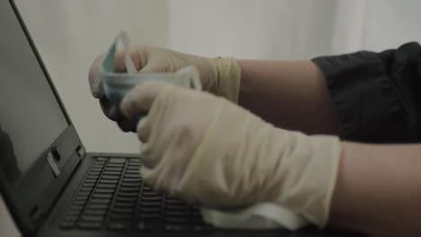 persona que usa guantes quirúrgicos mirando la máscara quirúrgica en una computadora portátil