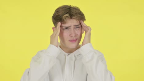 joven con dolor de cabeza en fondo amarillo
