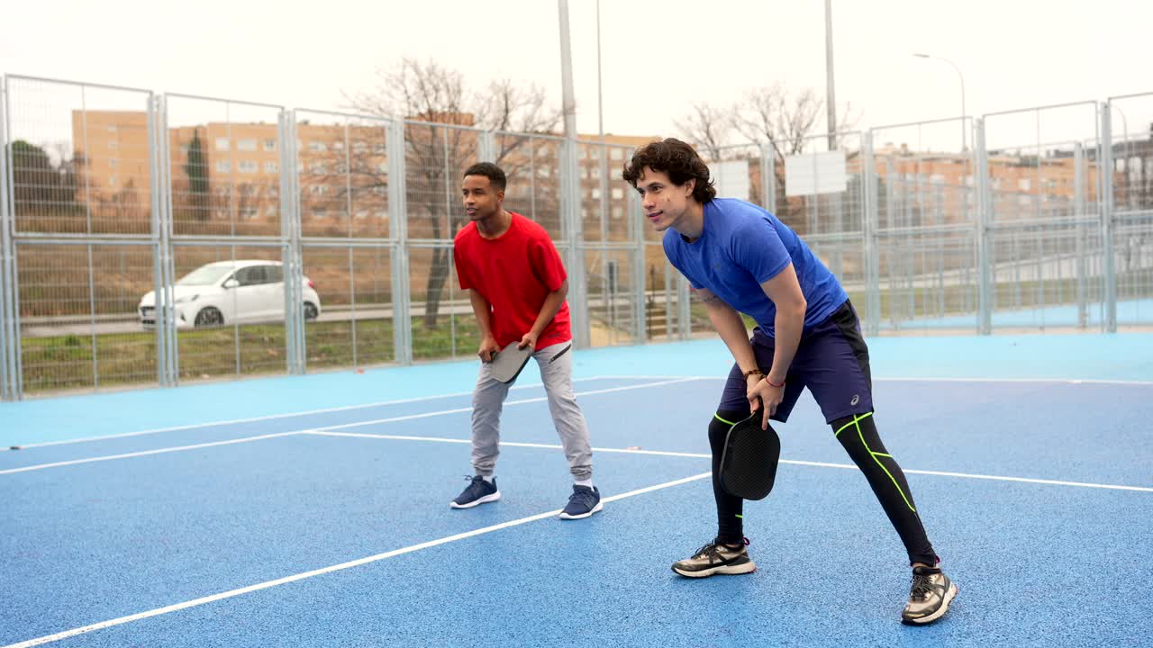 Two Young Men Playing Pickleball on an Outdoor Court