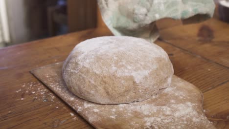 placing sourdough on a wooden board in the kitchen for resting - close up slowmo