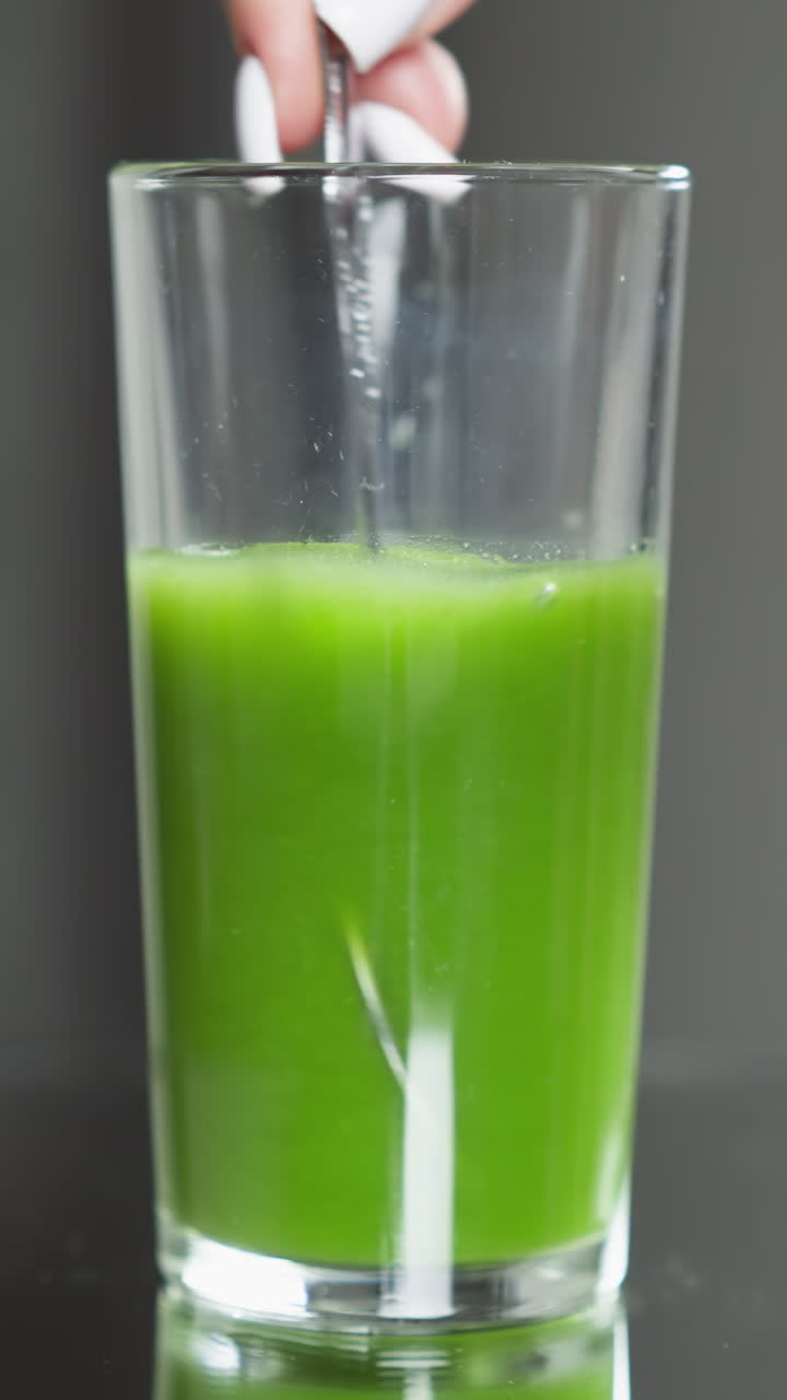 el dedo índice presionando suavemente la superficie del jugo de verduras verdes frescas en un vaso transparente