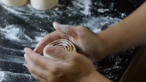 rollo de canela recién cortado al que se le da forma con harina seca usando los dedos en la mesa de la cocina filmado como un primer plano extremo