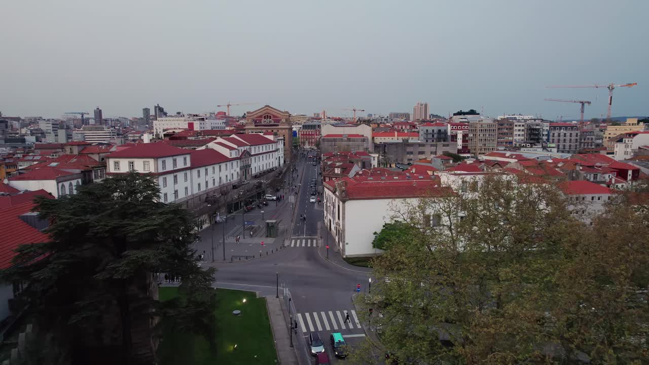 Vista aerea del paesaggio urbano di Porto, che cattura il paesaggio urbano, l'architettura tradizionale con i tetti rossi, le strade trafficate che collegano edifici storici e il moderno skyline in lontananza sotto un cielo nuvoloso
