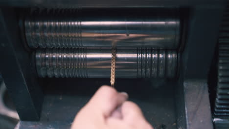 goldsmith-forge-rolls-shiny-chain-with-tool-in-shop-closeup