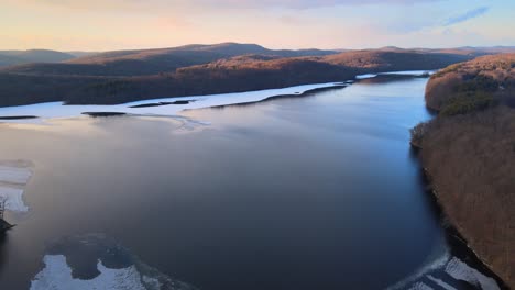 Imágenes-Aéreas-De-Drones-De-Un-Lago,-Colinas,-Montañas-Y-Bosques-Parcialmente-Congelados-Durante-La-Puesta-De-Sol-En-Las-Montañas-Apalaches-Durante-El-Invierno