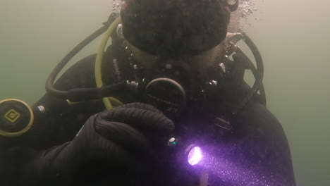 scuba diver shining a torch searching underwater in poor visibility