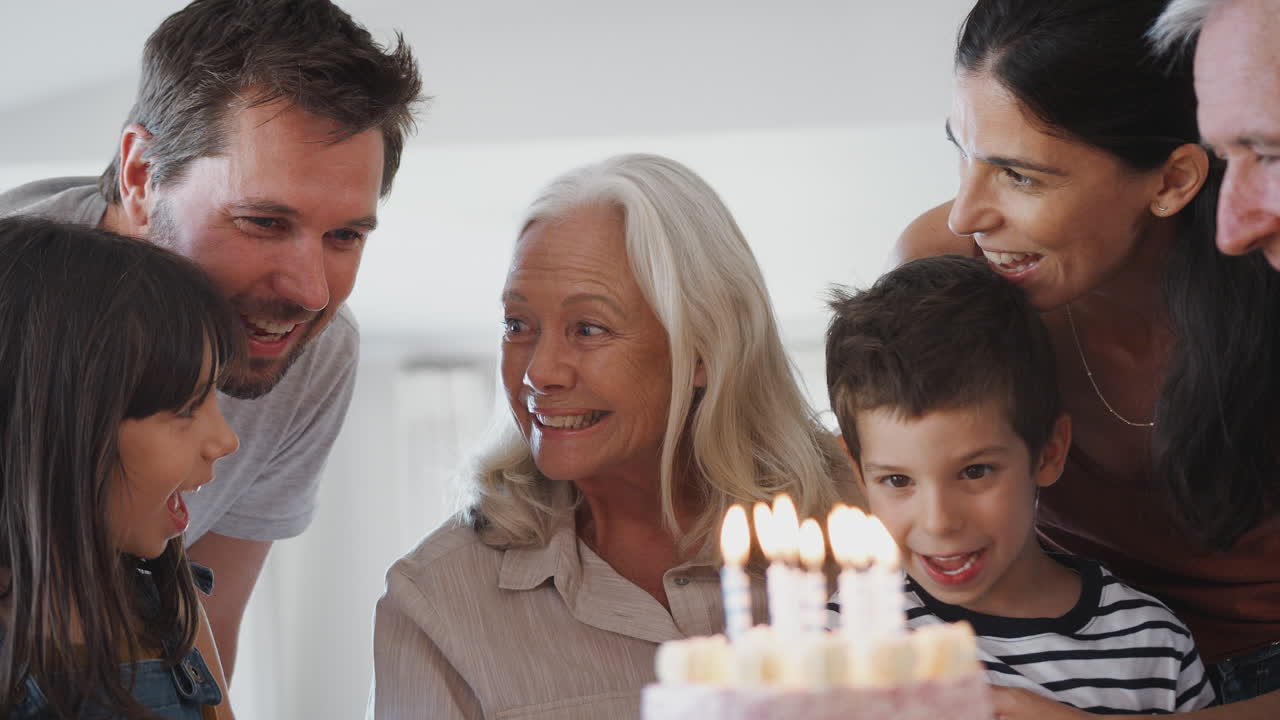 다세대 가족 이 손자 와 함께 생일 을 축하 하고 있으며, 손자 는  ⁇ 불 을 꺼내고 있다