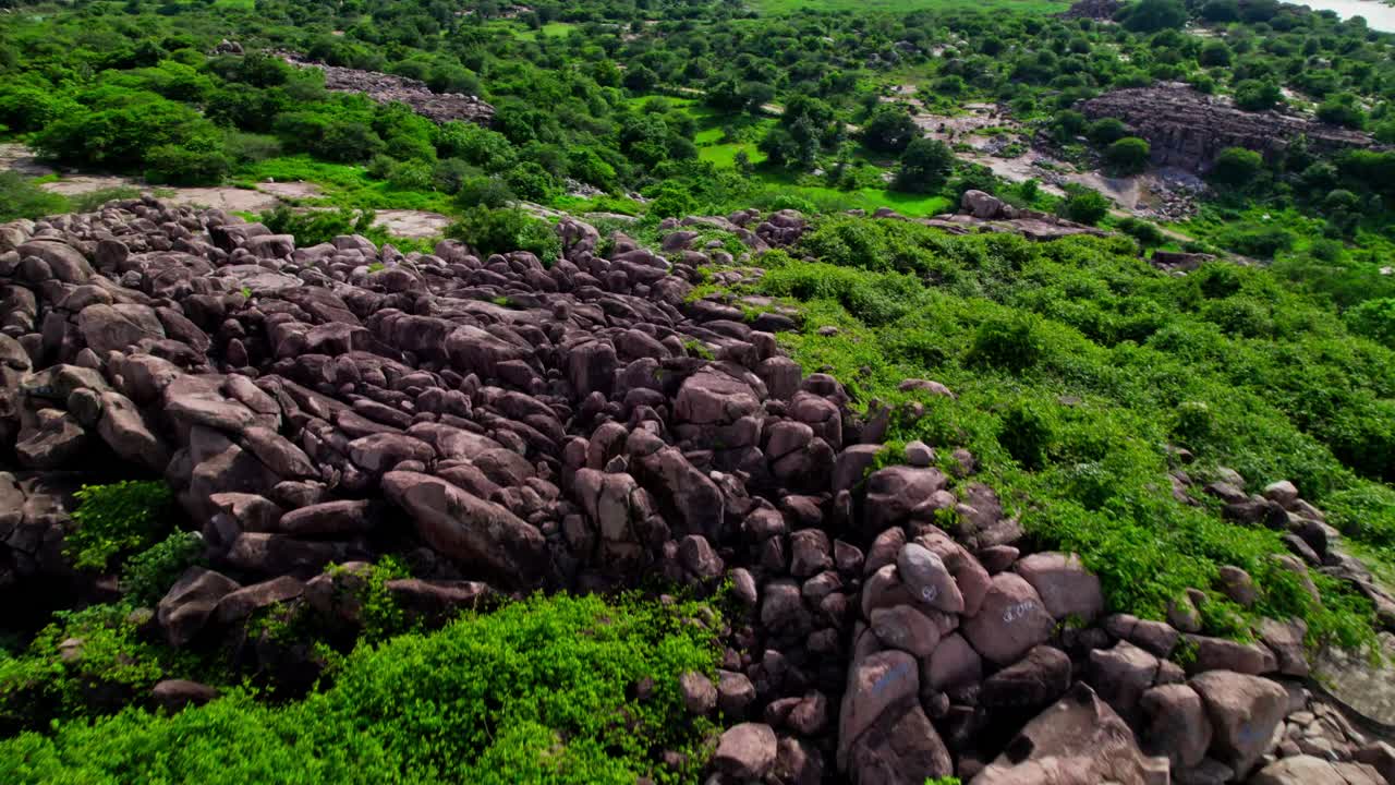 Granite hill with greenery and crop field land at yelupugonda village, Tekmal, telangana, india. day time, push in, drone shot, 4k.