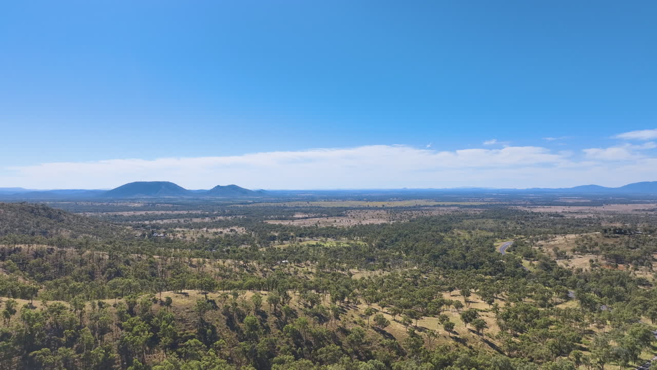 cruceros aéreos sobre las colinas boscosas y las llanuras al suroeste de rockhampton hacia el perfil lejano de la montaña de la mesa por boongary
