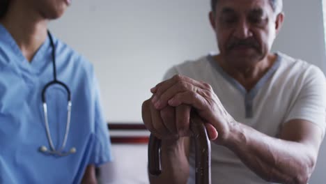 primer plano de un hombre de raza mixta con una doctora visitando la casa tomados de la mano