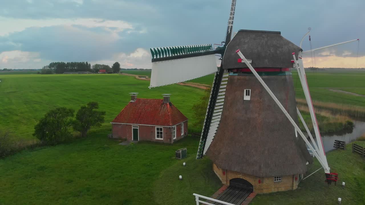 Vista aerea di un mulino a vento e una casa tradizionale che risplendono alla luce dell'alba a Lollum, Frisia, Paesi Bassi.