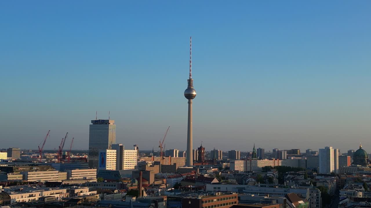 la torre de televisión de berlin de pie alto sobre la torre y el ayuntamiento rojo, bañado en el cálido resplandor de la hora dorada. magnífica vista aérea vuelo ascendente drone