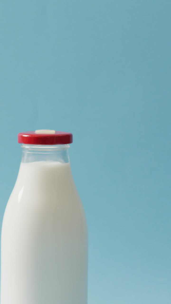 video de una botella de vidrio de leche sobre un fondo azul