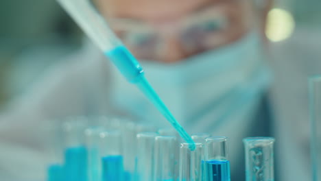 female microbiology scientist working with blue liquid in lab