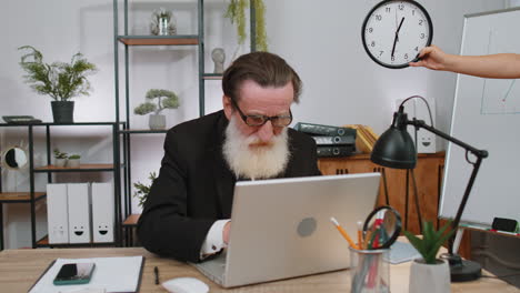 business man working on laptop at office with anxiety checking time on clock being late, deadline