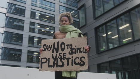 toma en ángulo bajo de una joven activista climática estadounidense que protesta contra los plásticos de un solo uso mientras mira la cámara