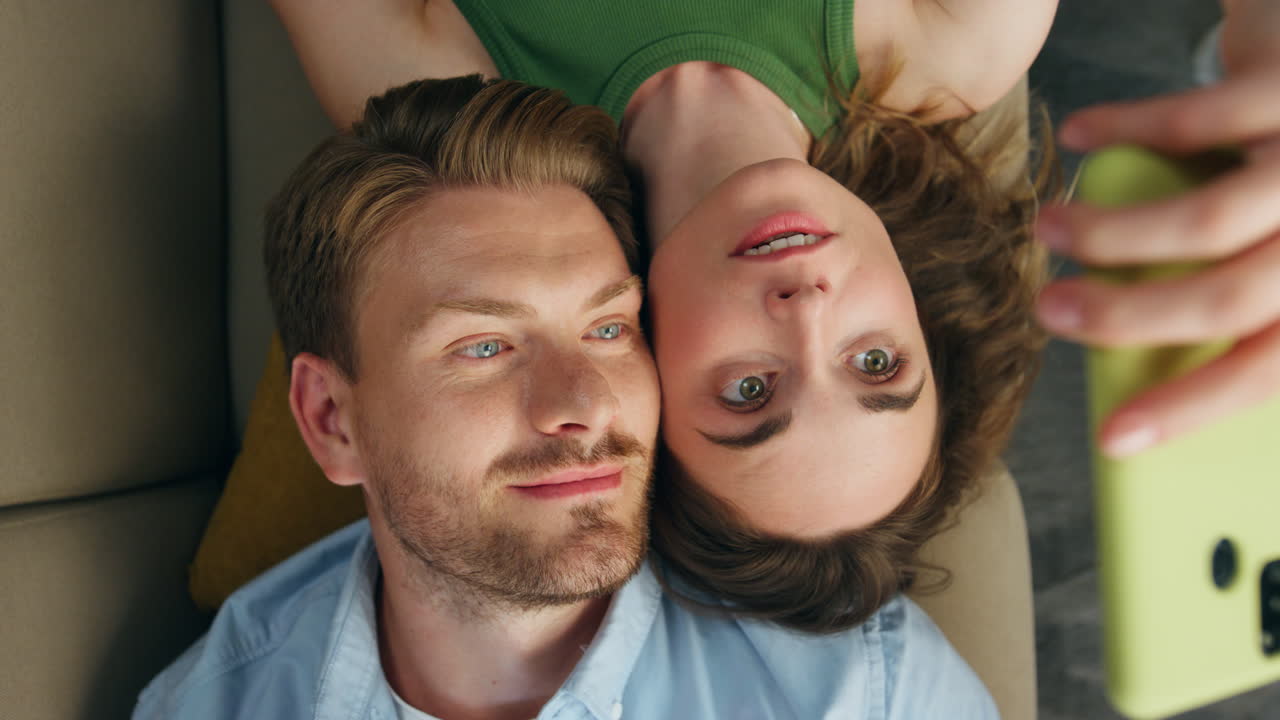 милые любовники фотографируют смартфоны холодный диван крупный план. женщина делает селфи