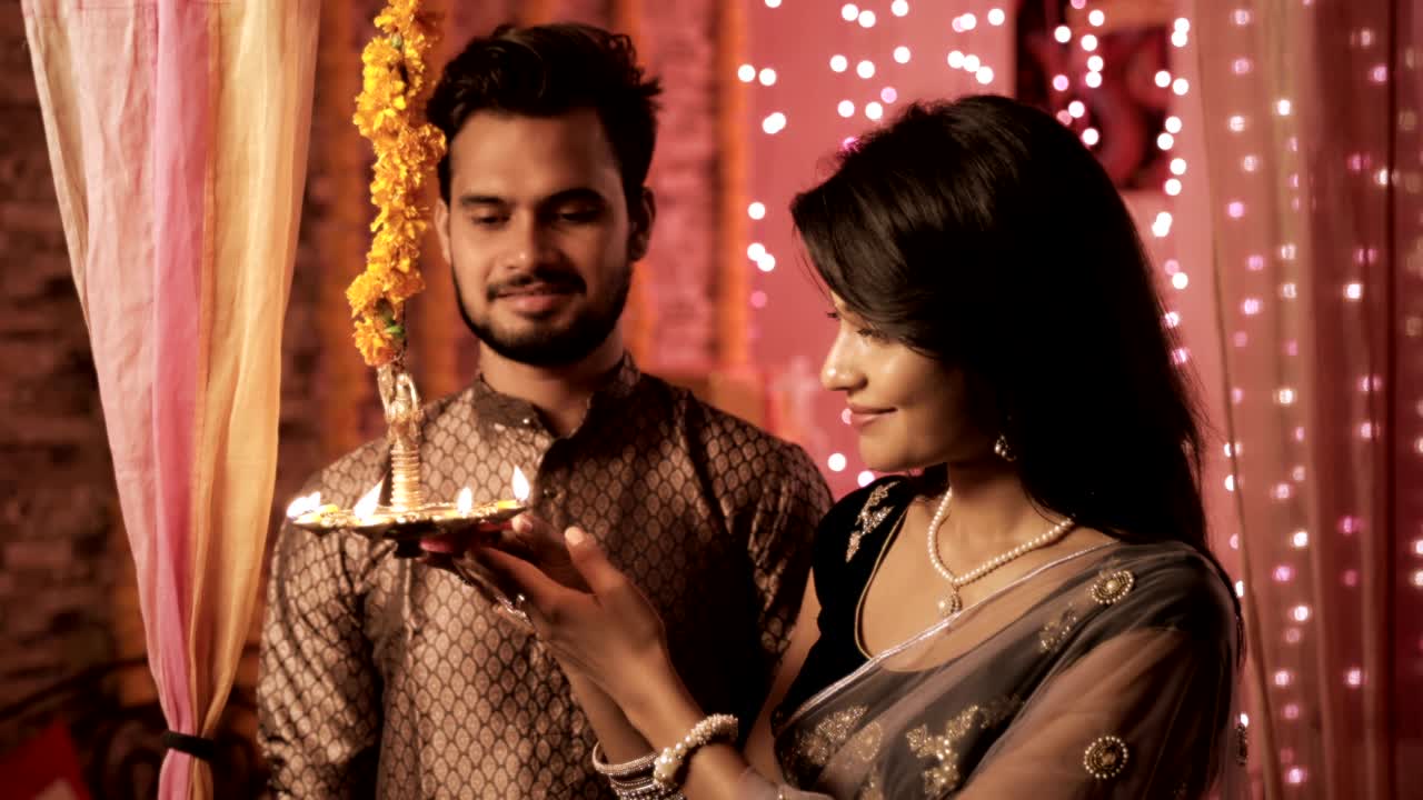 A happy husband and wife in a house interior decorated with lights and flowers.