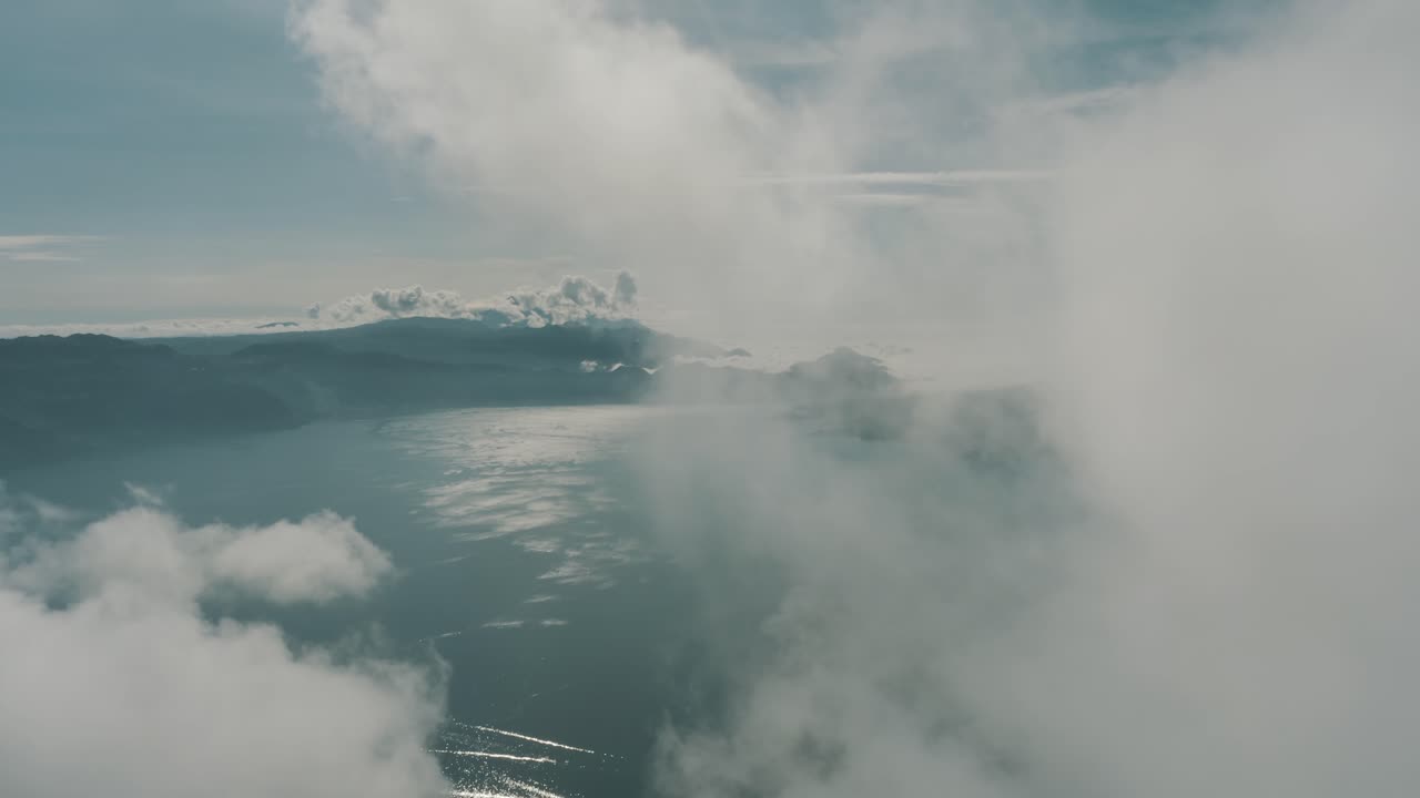 drone aéreo volando alto a través de las nubes revelando el hermoso lago azul atitlan en guatemala