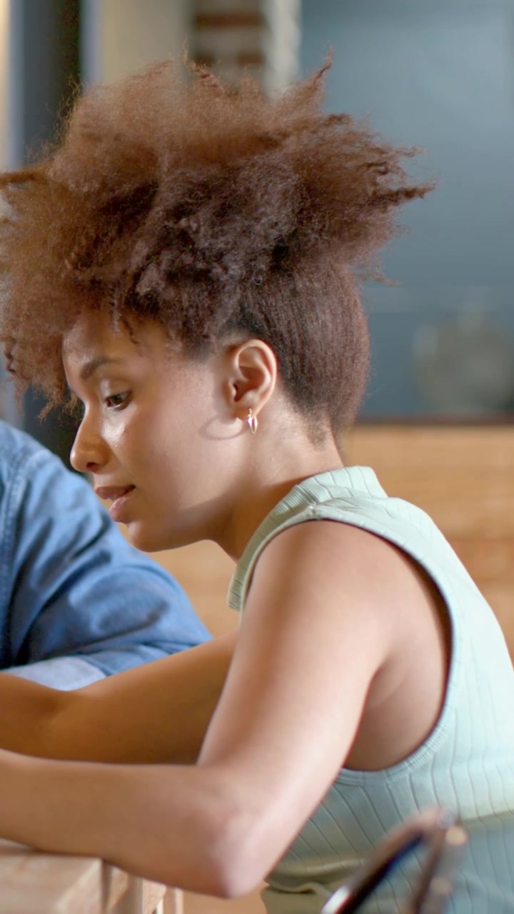Vertical video: Reading notes, woman in green top explaining plans at cafe table, checking watch