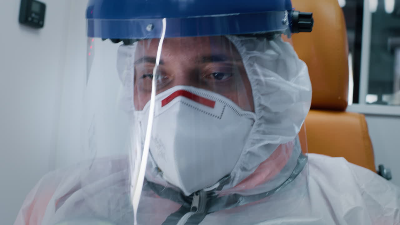 tired Paramedic in Hazmat Suit Exhausted Man in Hazmat Suit with Face Shield and Mask Looking Away while Riding Ambulance during Epidemic