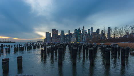 wood pilings at old pier 1 in brooklyn bridge park with new york financial district skyline in usa