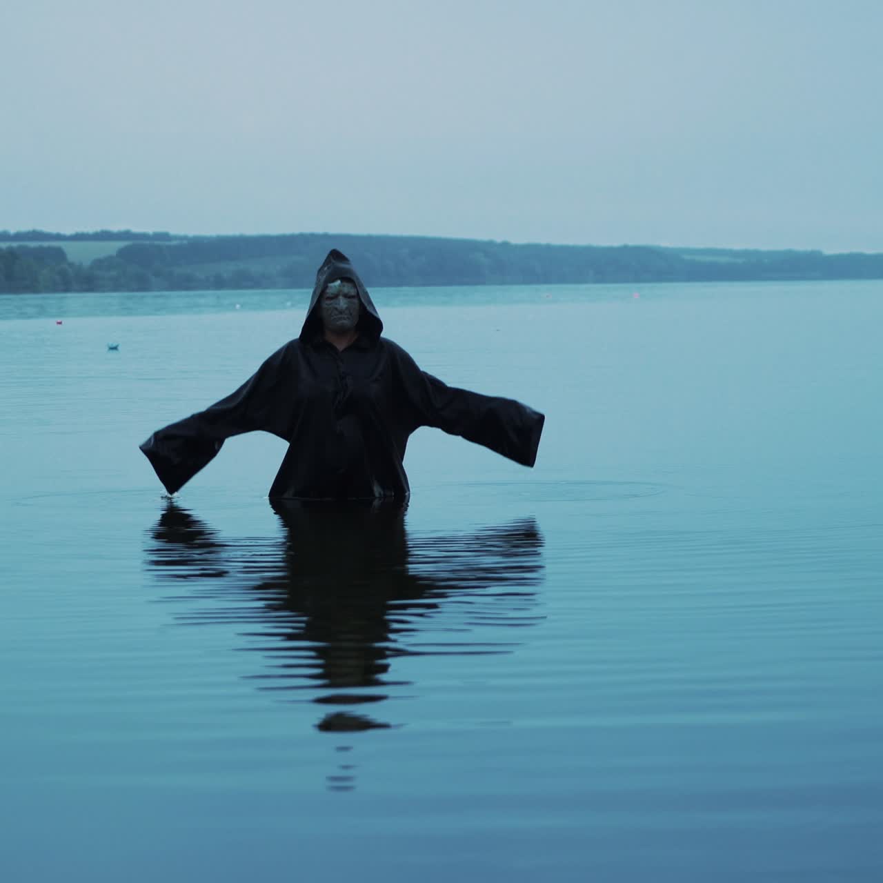 Scary figure in black mantle. Horror woman soaking in water river.