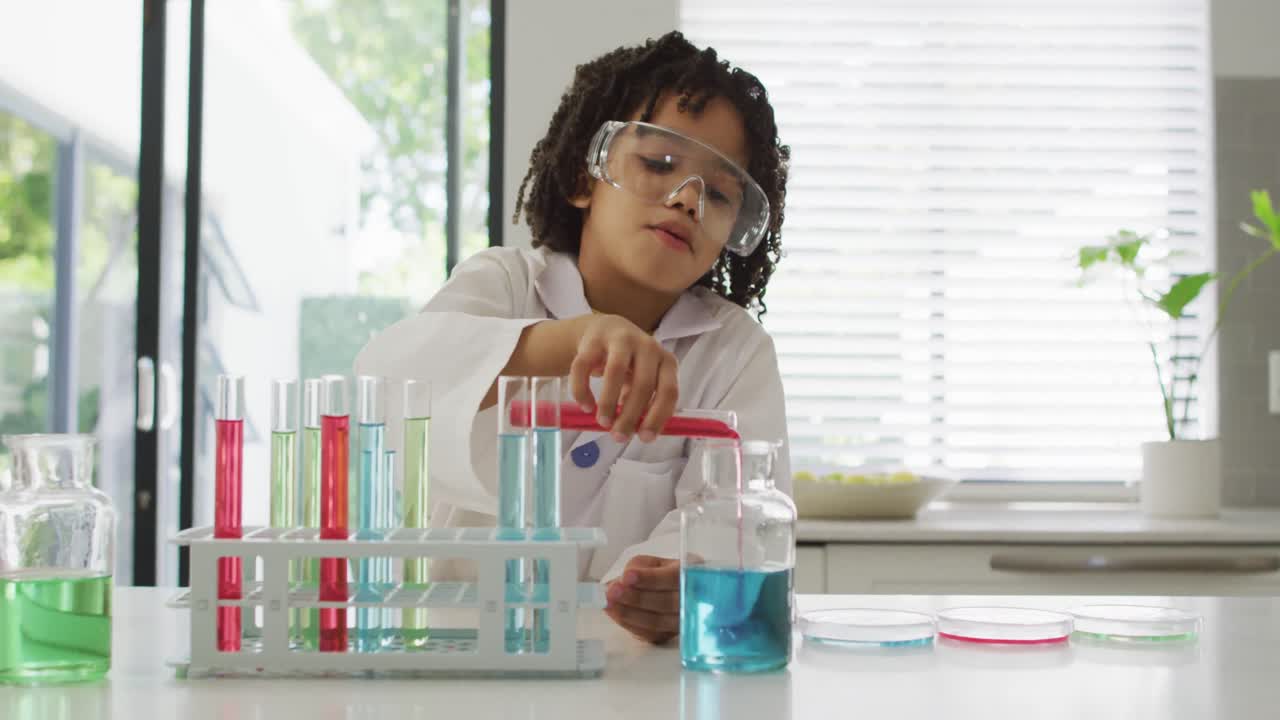 feliz muchacho biracial haciendo experimentos de química, sosteniendo un tubo de ensayo