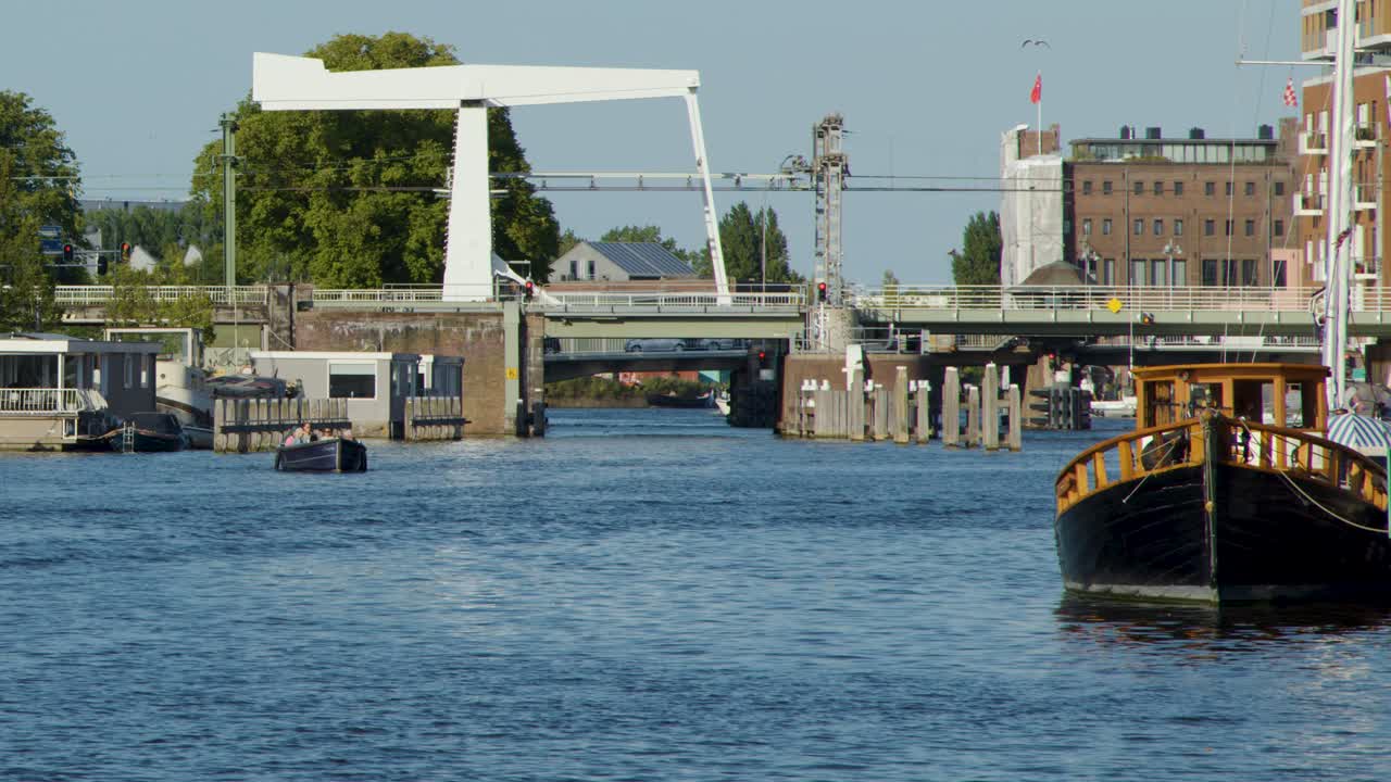 Large boat moves toward white drawbridge on sunny canal, steady camera, clear blue sky