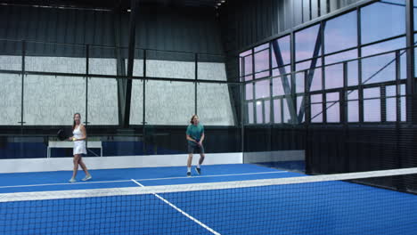 high-fiving on padel tennis indoor court, diverse athletes celebrating victory together