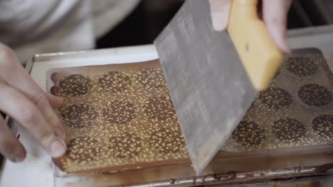 laying plastic film cover on chocolate mould using scraper