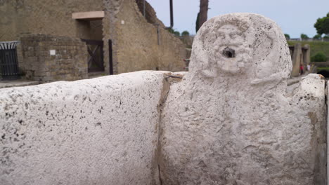 ancient stone fountain with carved face at an archaeological site