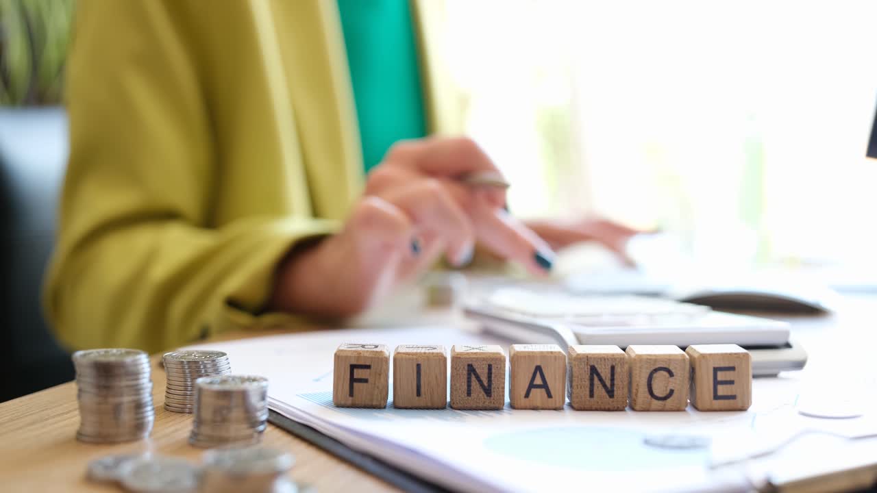 Finanztext auf Würfeln und arbeitende Geschäftsfrau mit Dokumenten und Taschenrechner
