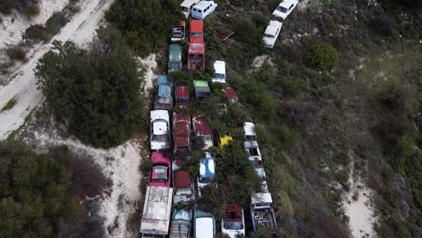 aerial pullback over old antique cars in a junkyard