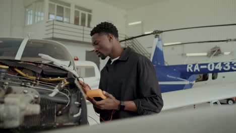black mechanic performing engine diagnostics on aircraft in hangar