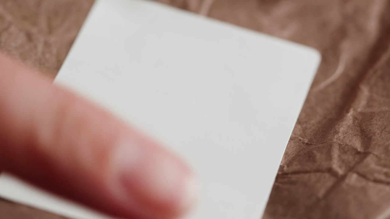 Hands holding a blank white label on brown paper