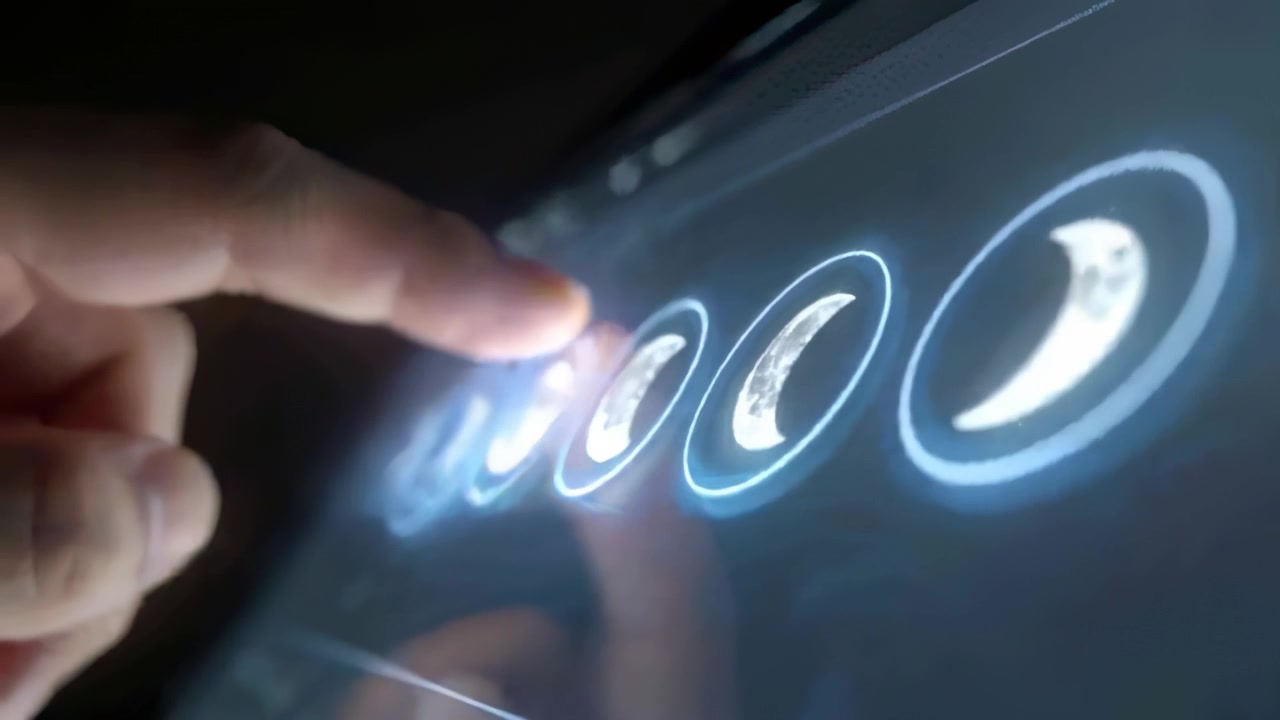 Approaching from left, finger tapping tablet in dark room producing ripples and selecting crescent