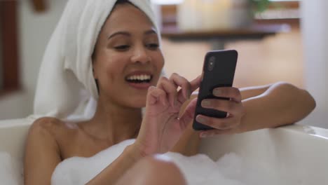 Mujer-De-Raza-Mixta-Tomando-Un-Baño-Y-Usando-Un-Teléfono-Inteligente