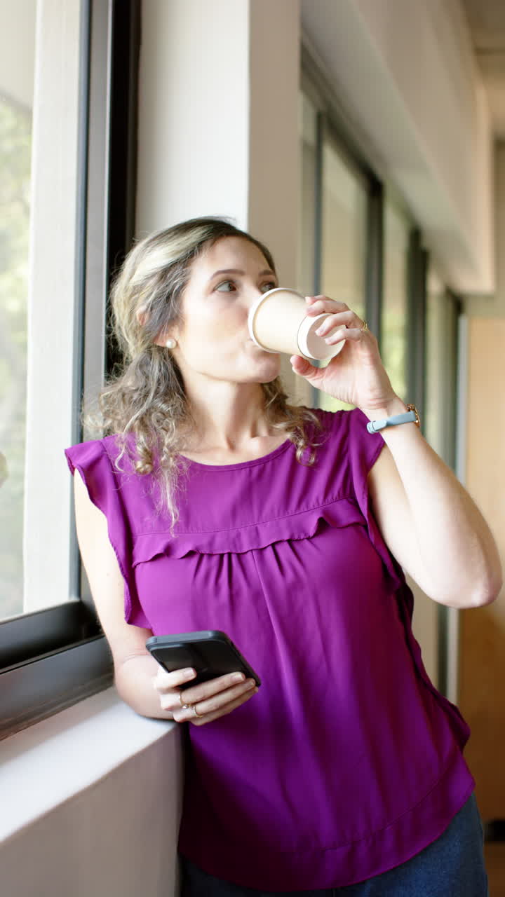 Vertical video of caucasian casual businesswoman using smartphone in office, slow motion