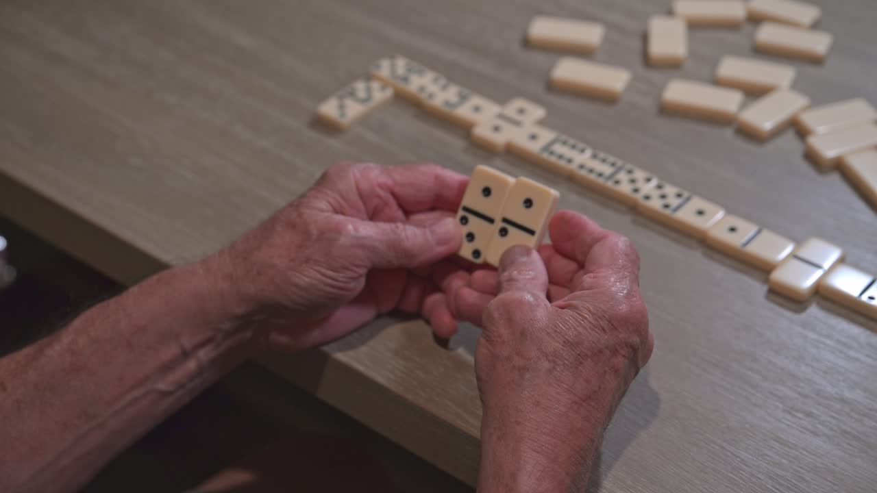 el anciano tiene dos dominó esperando para jugar su estrategia ganadora