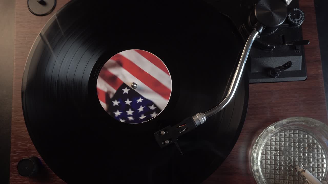 Disco in vinile con adesivo della bandiera americana, sigaretta nel portacenere, vista dall'alto