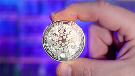 rack focus portrait of cardano ada silver coin being held between fingers