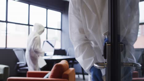 cleaners wearing protective clothes sanitizing modern office space