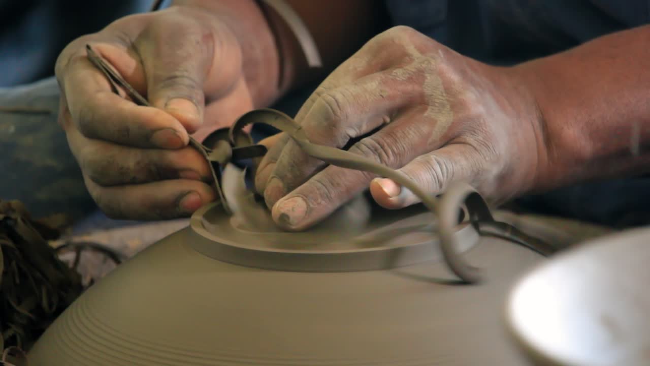 Worker in pottery studio using pottery wheel, handmade ceramics