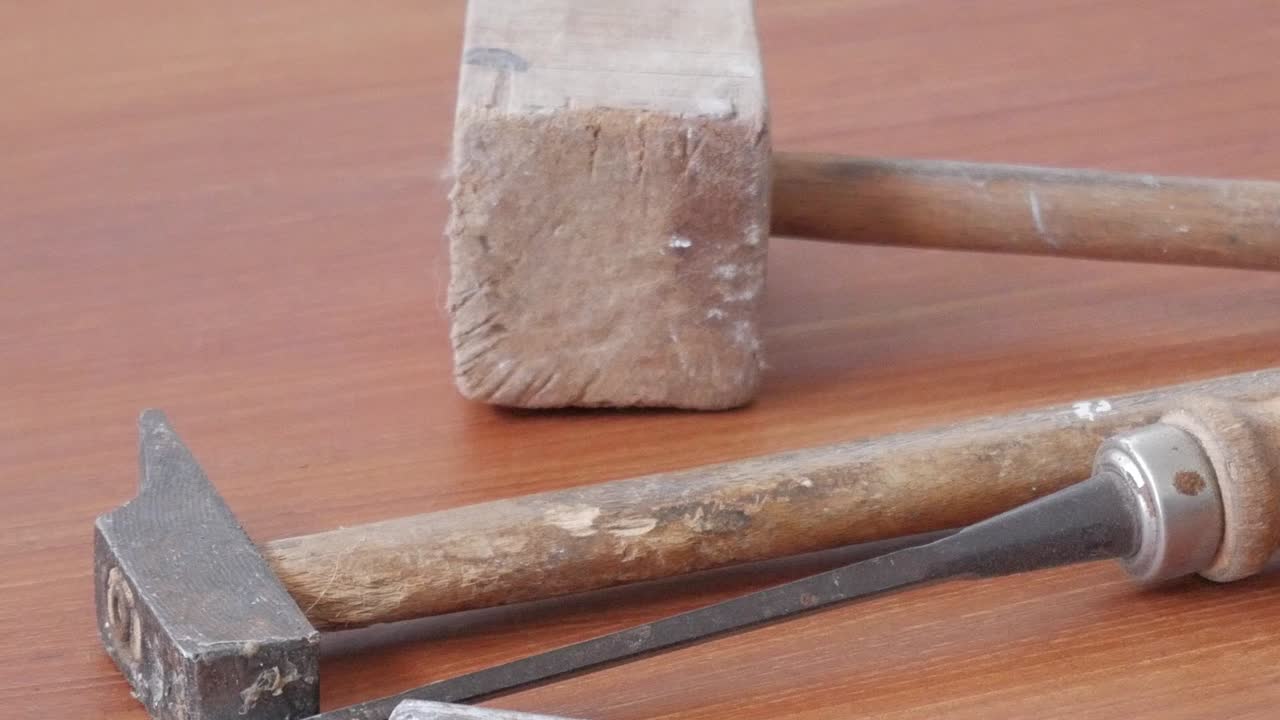 Detailed close-up of an antique woodworking hammer and chisel resting on a wooden table