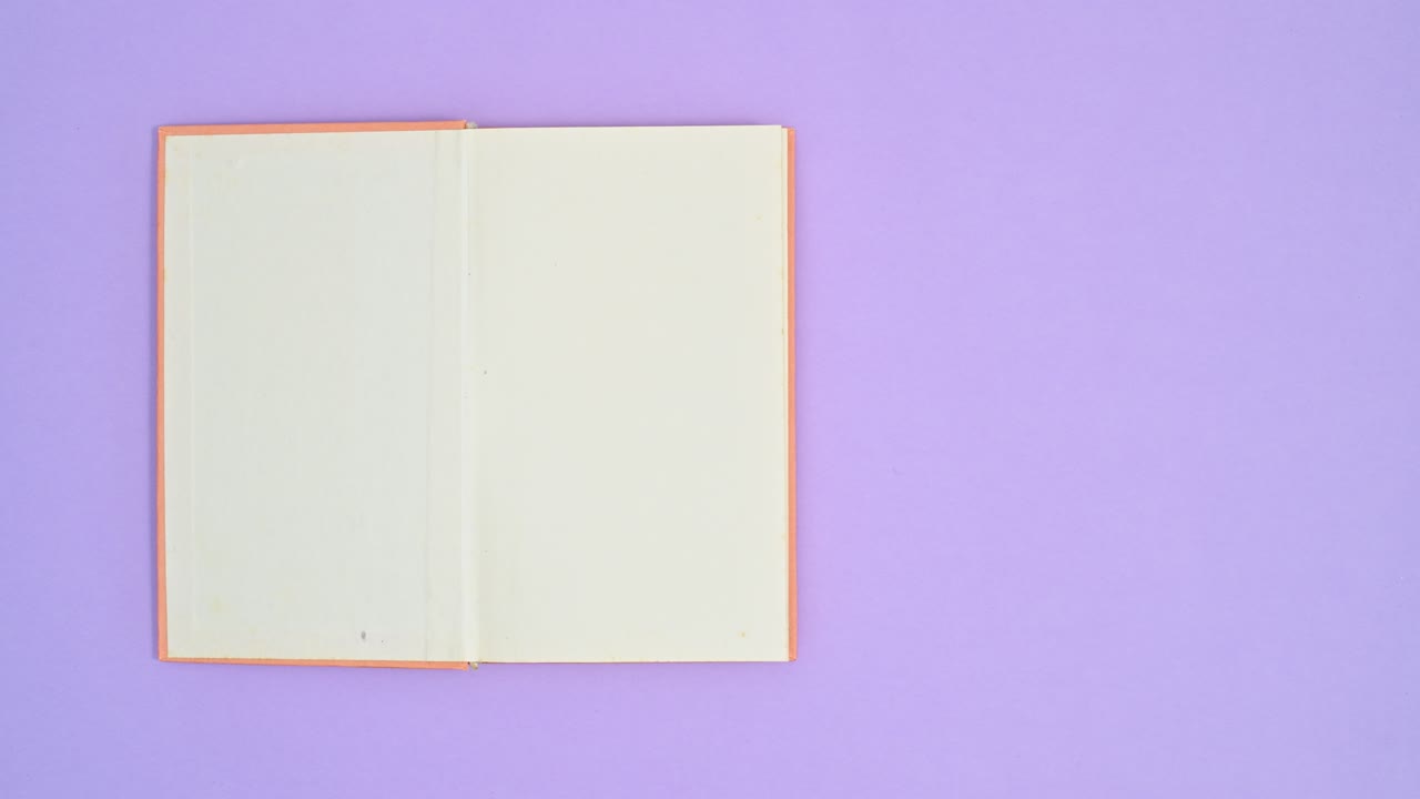 Orange hardcover vintage book appear on purple theme and open. Stop motion flat lay