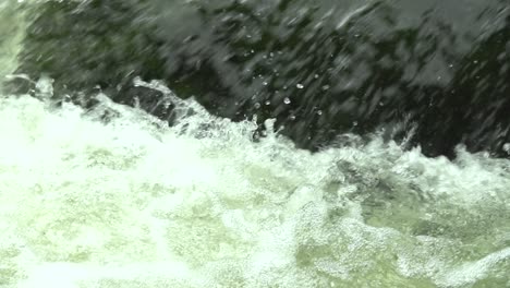 Frisch-Fließender-Wasserbach-Mit-Wassertropfen-In-Der-Natur-Mit-Einem-Stein-Im-Hintergrund,-Zeitlupe,-Nahaufnahme